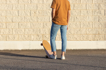 Young man on his back using his skate board in the city against a white brick wall at sunset time in spring