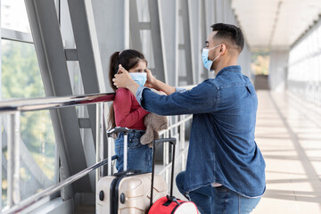 Caring Arab Father Wearing Protective Medical Mask To His Daughter At Airport