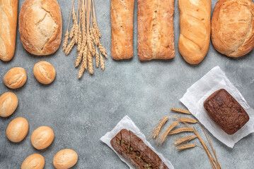 Fresh bread on a gray concrete background. Assortment of various bakery products. Top view, flat lay.