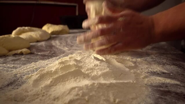 Men's hands hold dough. making raw dough for pizza, rolls or bread. Handmade. Wheat pastries in bakery products. Production of bakery products. Men's hands knead dough. protven or countertop.