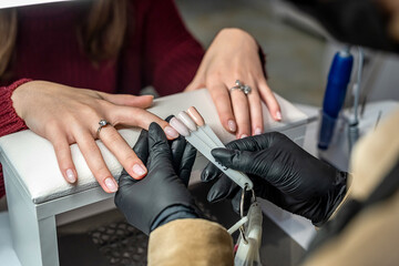 Manicure master with client in beauty salon chooses color of gel polish