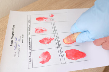 close-up of finger makes fingerprint using special red paint, documents police examination of suspected person, personality identification concept, sweat traces from crime scene, police investigation