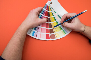 man choosing color in wheel palette isolated on orange