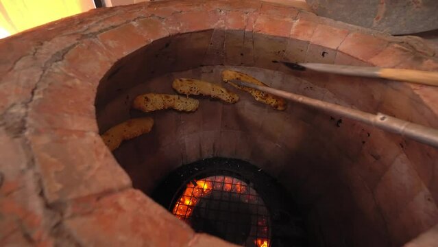 Tandoor. Inside oven, fire burns and flat bread is baked on walls. Khachapuri. Georgian cuisine. Bakery or bread production. Work from gas. Culture of Georgian or Oriental cuisine.
