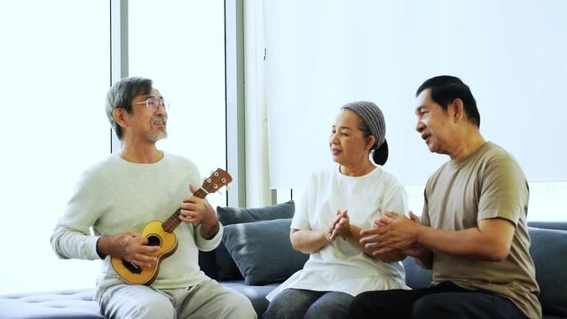 A group of elderly people are singing and playing guitar in the living room.