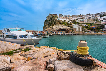 Port of Peschici, with the town perched on the cliff overlooking the sea and a ship anchored to the...