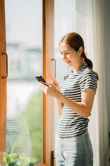 Beautiful Asian woman standing and chatting with friends on mobile phone typing messages on the Internet. Communication concept, close-up