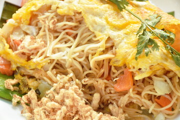 fried rice noodles with vegetable wrapped egg topping dry shredded pork on plate