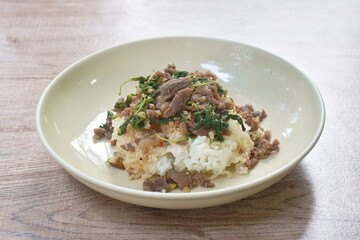 spicy fried slice beef meat with basil leaf and chili topping on rice in plate