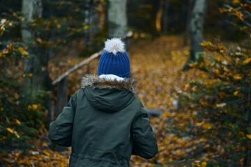 Girl in a warm hat and warm jacket. Rear view. Beautiful autumn season. 