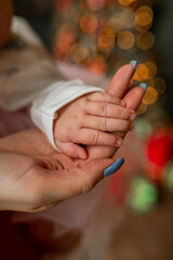Children's hand in the palm of the mother, blue manicure. Blurred lights in the background