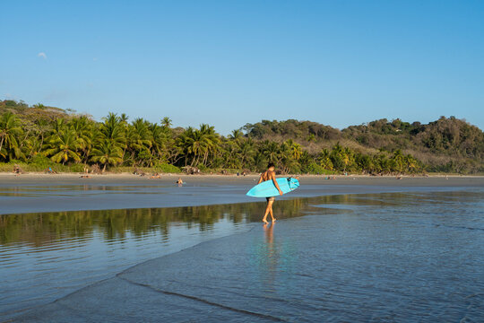 Surfer walking at the beach at beautiful Playa Hermosa in Santa Tersa, Costa Rica.
