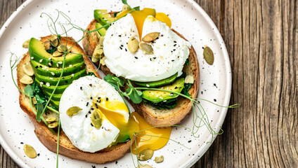 Poached egg on on bread with spinach, avocado and pumpkin seeds, Healthy food, keto diet, diet lunch concept. Top view