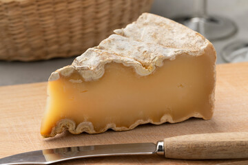 Piece of mature French Mountain Abbey cheese on a cutting board close up