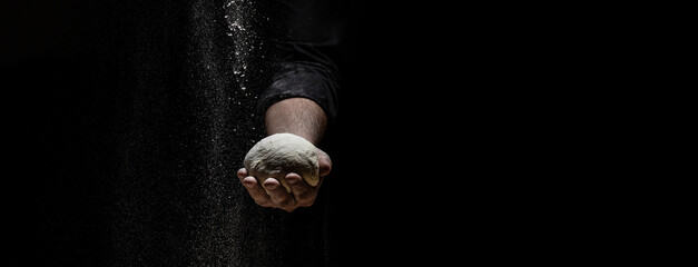 White flour flying into air as pastry chef in white suit slams ball dough on white powder covered...