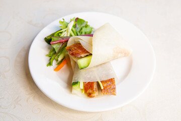 Roast Peking duck set combo with vegetable and sweet sauce and roll roti bread of traditional Cantonese yum-cha Asian gourmet cuisine meal food dish, with steam basket container and white table