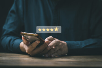 Customer Satisfaction Survey Concept, A man's hand using a smartphone gives a 5 star rating to show...