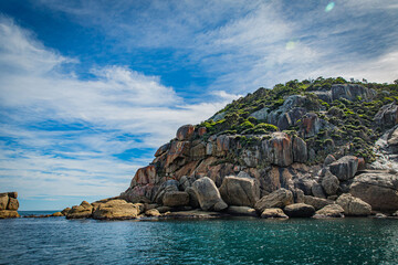 Obraz premium Stone rock mountain forest seascape in Cruising tour view in the Bass Strait at Wilson Promontory Victoria Australia, blue sky and blue sea