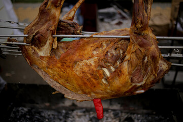 lamb on a spit. Whole lambs baked on a spit, direct on fire outdoor. Street food. Spit-roasted meat. Traditional Caucasian cuisine. Smoked meat in the smoke and on an open fire.