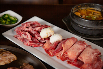 Korean Grilled BBQ combo with wagyu beef set on the traditional grill table, with lettuce, soup, mushroom and pickle dishes