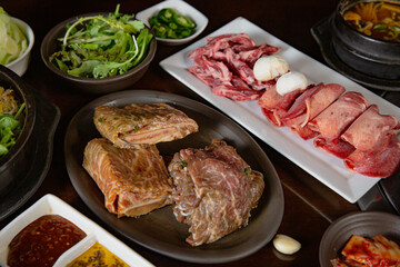 Korean Grilled BBQ combo with wagyu and marinated beef set on the traditional grill table, with lettuce, dipping sauce, rice and pickle dishes