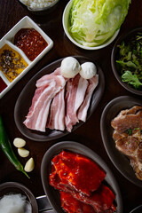 Top view Korean Grilled BBQ combo with pork belly and marinated pork set on the traditional grill table, with lettuce, dipping sauce and pickle dishes