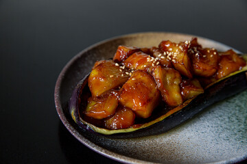 Roast eggplant in the kaiseki fine dining Japanese restaurant, with a fine black plate in black scene background