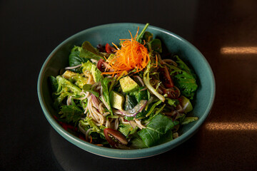 Japanese avocado noodle salad in the fine dining Japanese restaurant, with a green round bowl in black scene reflection table background