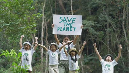 Asian teachers and group children holding a sign with the message "Save The Planet" Activities aimed at instilling a sense of reverence for the natural world and the environment, saving the world