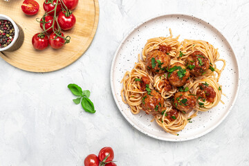 Meatballs served over italian spaghetti pasta with tomato sauce on a light background. Italian...