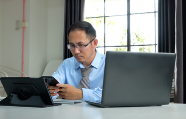 Man using a laptop computer and phone at work in a office, online study, internet marketing, working from home, office workspace freelance concept