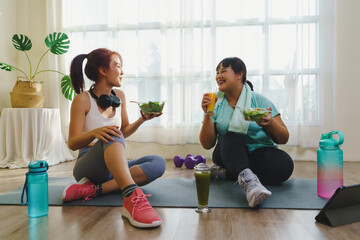 Fitness and Healthy food concept. Two Asian women body size is different in sportswear sitting...