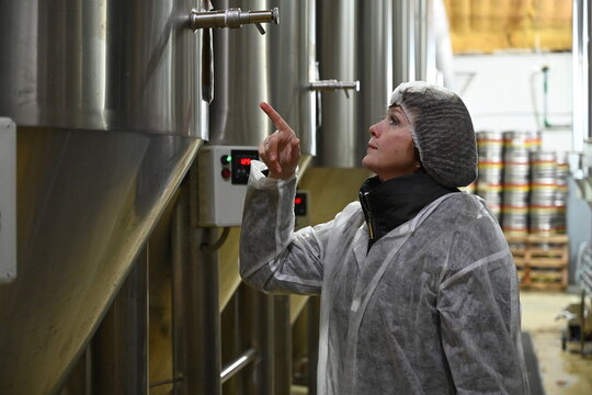 Woman worker controls the process of making beer - Powered by Adobe