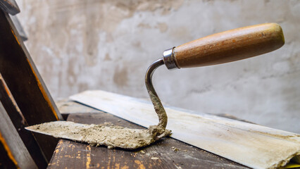 Close-up of a dirty trowel against a wall with plaster. Wall renovation process. Renovation concepts.