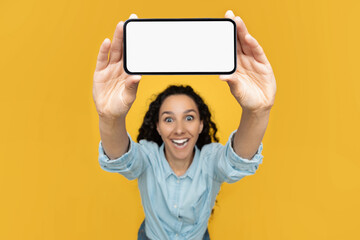Excited lady showing blank mobile phone screen at studio