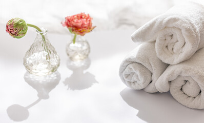 Close-up, white terry bath towels and flowers.