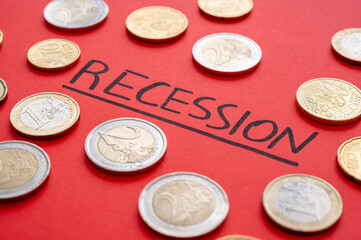 Text "recession" written on red surface and few coins around. Poverty and economic difficulties due to recession and economic crisis.
