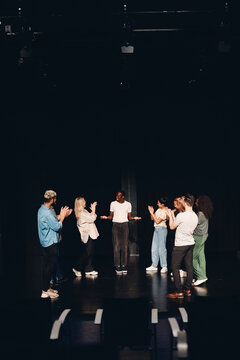Multiracial male and female stage performers applauding actor in class
