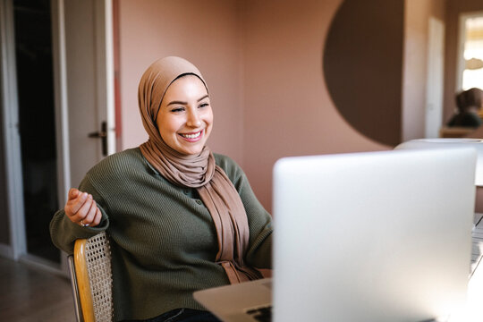 Happy young freelancer looking at laptop while working from home