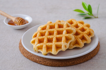 Waffles on white plate and honey in bowl