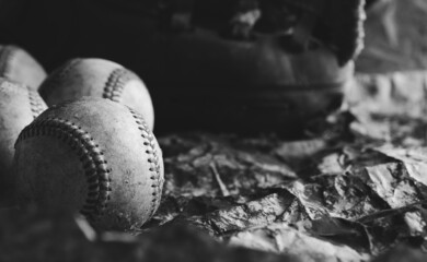 Old dark vintage baseballs with copy space on wallpaper background in black and white.