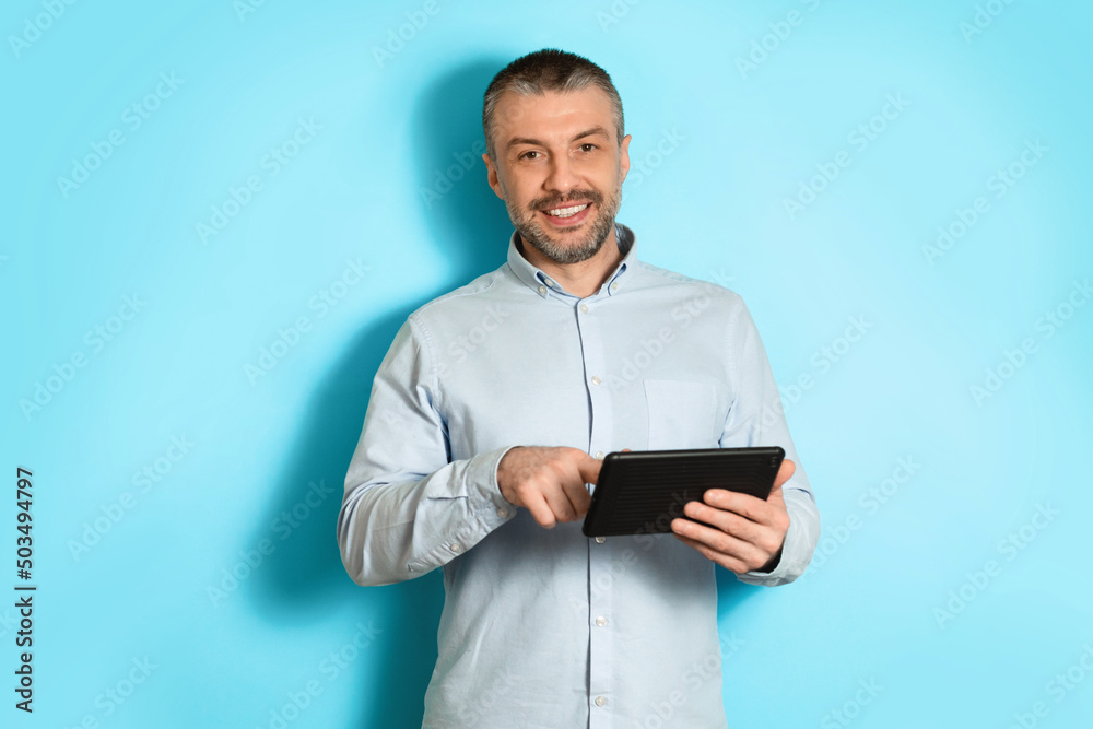 Poster Middle Aged Man Using Tablet Browsing Internet On Blue Background