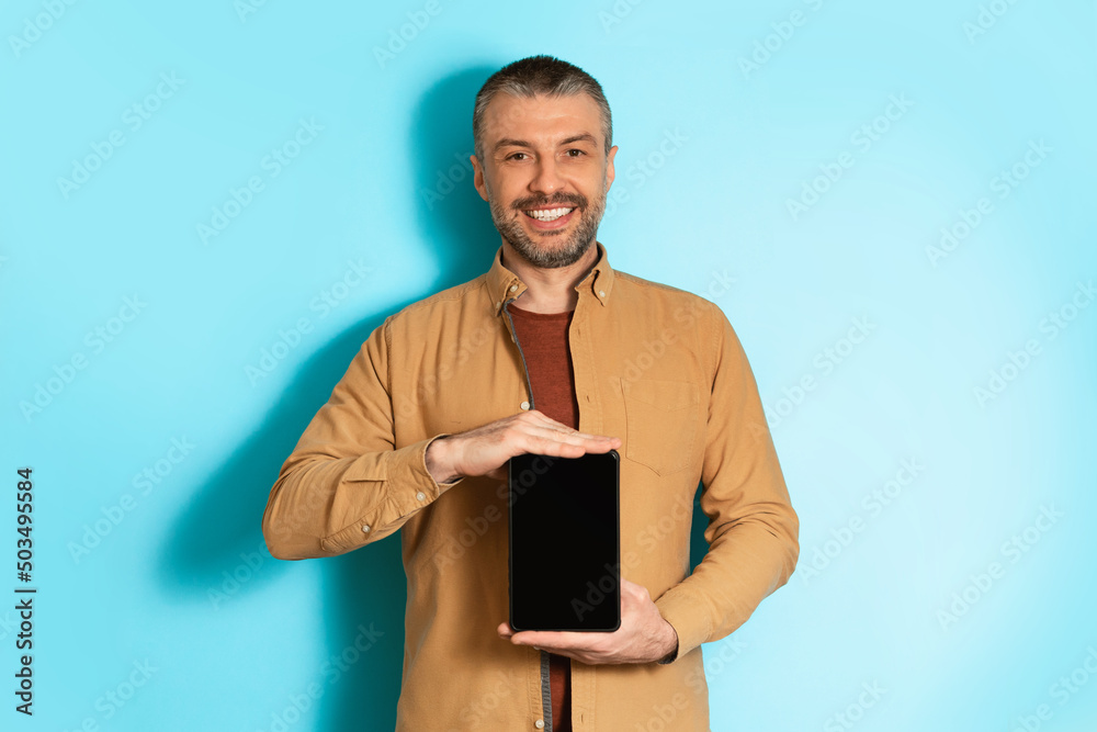 Poster male holding tablet computer with empty screen on blue background