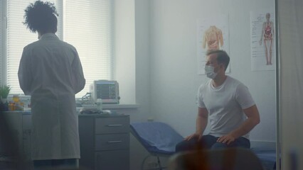 Woman doctor preparing covid vaccine in clinic. Patient waiting vaccination.