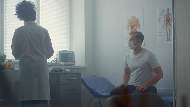 Woman doctor preparing covid vaccine in clinic. Patient waiting vaccination.