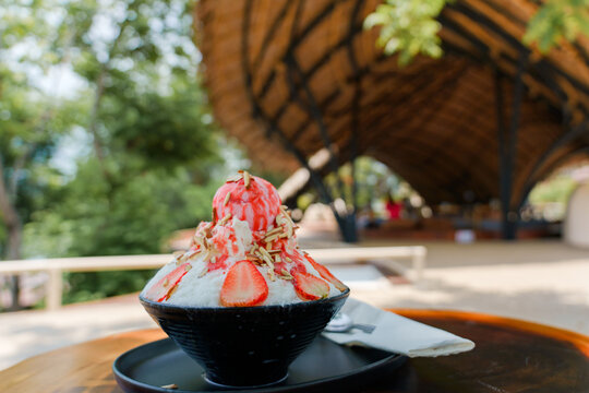 Japanese shaved ice dessert , Strawberry kakigori bingsu topped with sweet ice cream almond stick strawberry sauce and condensed milk in cafe. Traditional summer dessert menu in Japan.