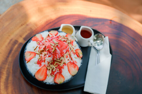 Japanese shaved ice dessert , Strawberry kakigori bingsu topped with sweet ice cream almond stick strawberry sauce and condensed milk in cafe. Traditional summer dessert menu in Japan.