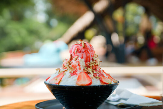 Japanese shaved ice dessert , Strawberry kakigori bingsu topped with sweet ice cream almond stick strawberry sauce and condensed milk in cafe. Traditional summer dessert menu in Japan.