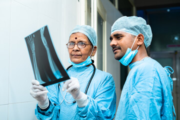 senior surgeon with practitioner discussing from xray report at hospital corridor - concept of communication, assistance and healthcare or medical service