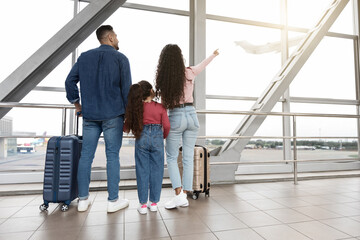 Fototapeta premium Family Of Three Looking Out Of Window At Airport And Pointing Away